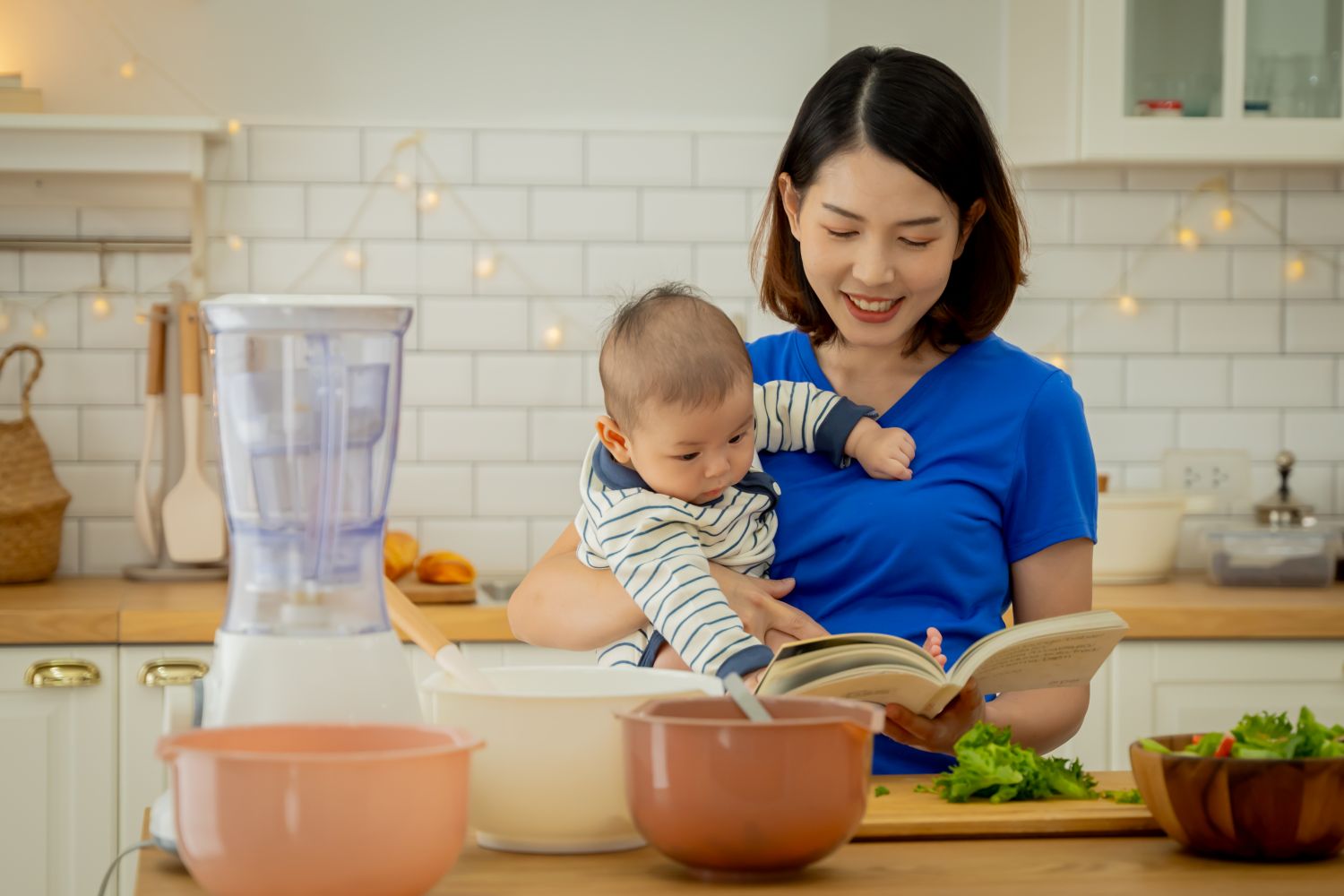 woman holding baby while reading cook book